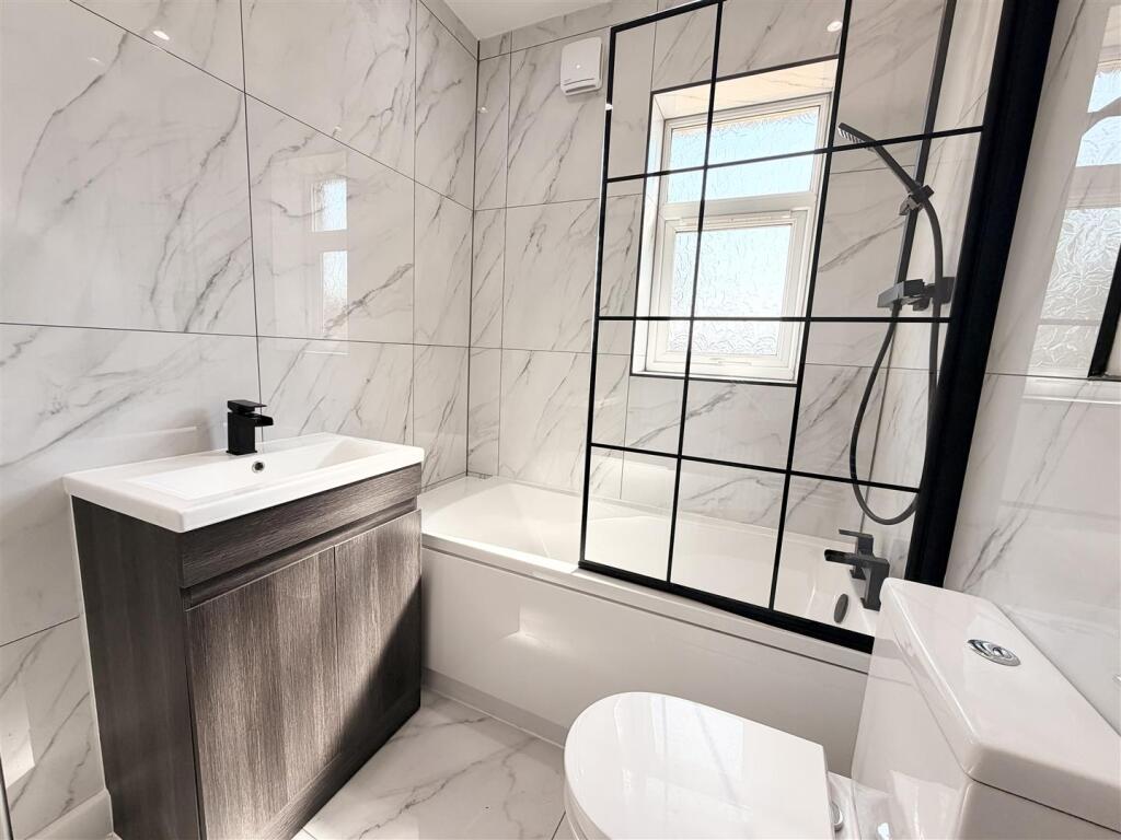 Bathroom with marble-effect tiling, black brassware and a crittall-style shower screen