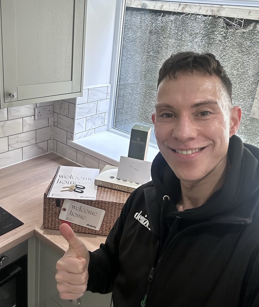 Ben Bates at a kitchen counter beside a Denizen welcome box, keys and a welcome home booklet, on the day a new resident moves in